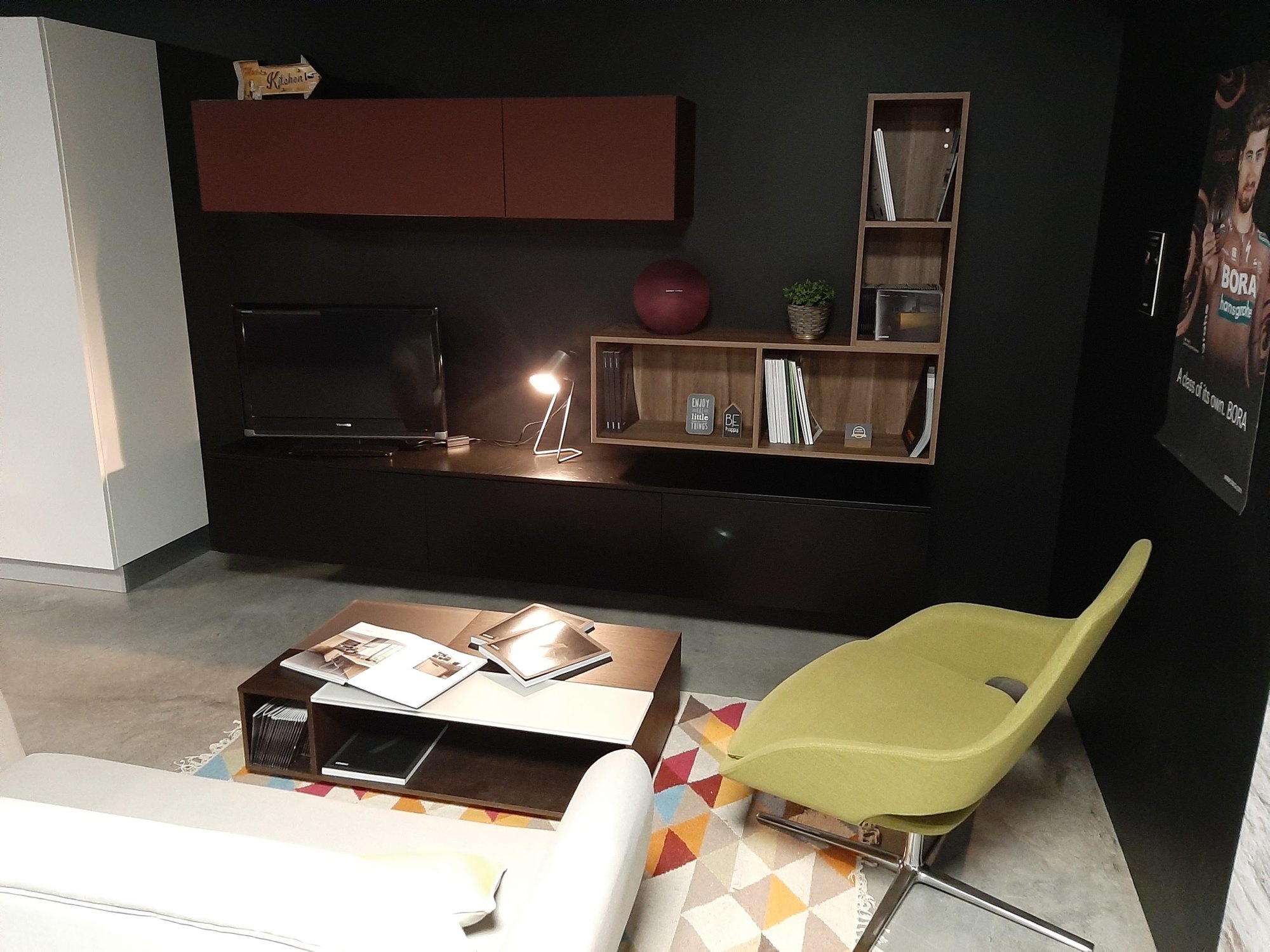 Salon avec meuble TV et rangements noirs et un fauteuil vert