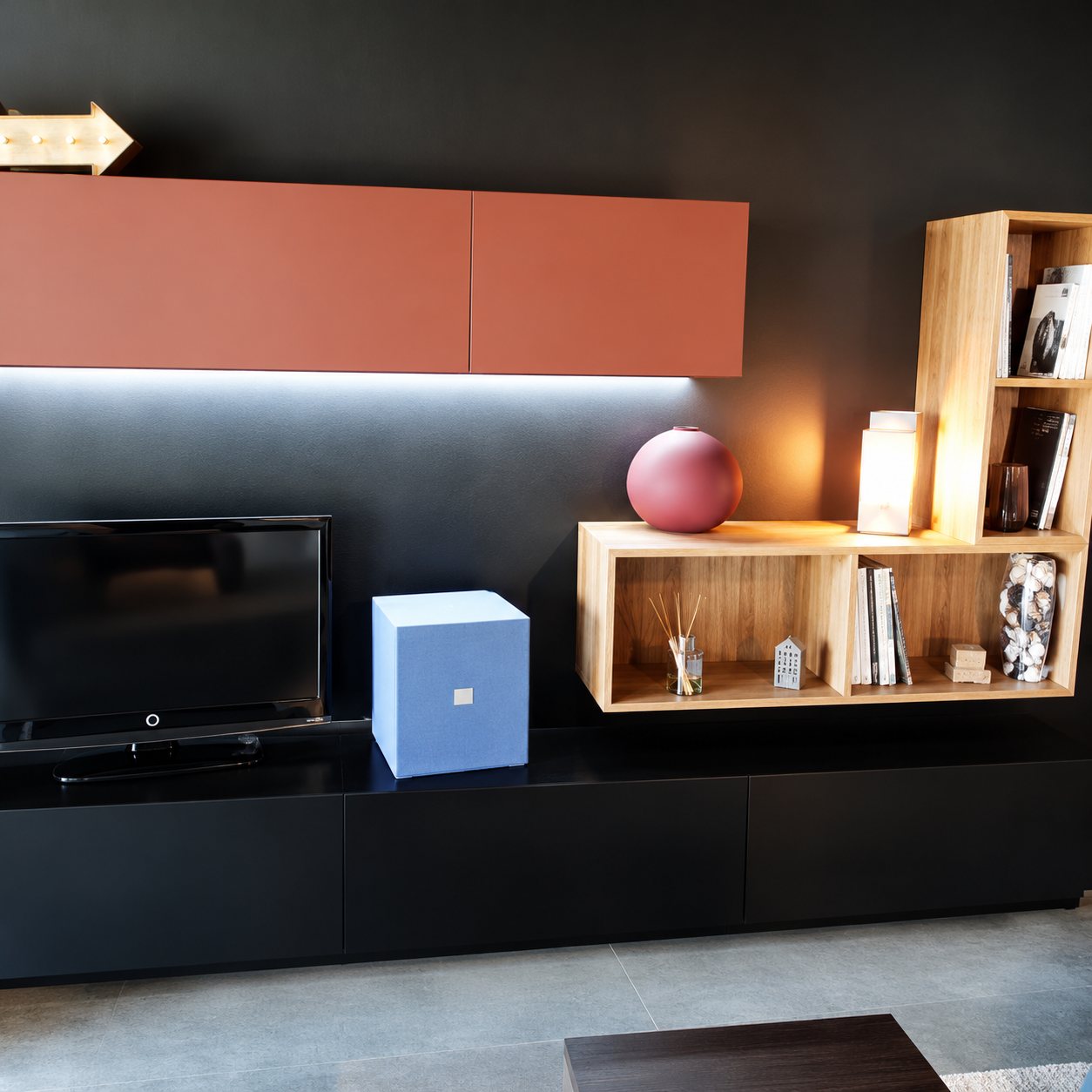 Meuble TV noir avec éléments muraux rouge brique et étagères en bois