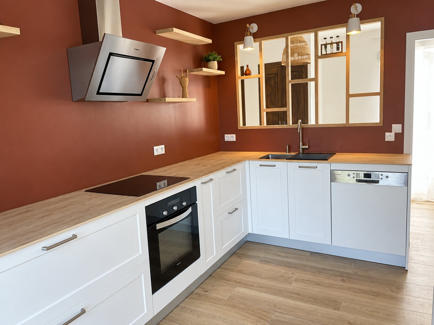 Cuisine blanche à plan de travail en bois et mur bordeaux après rénovation