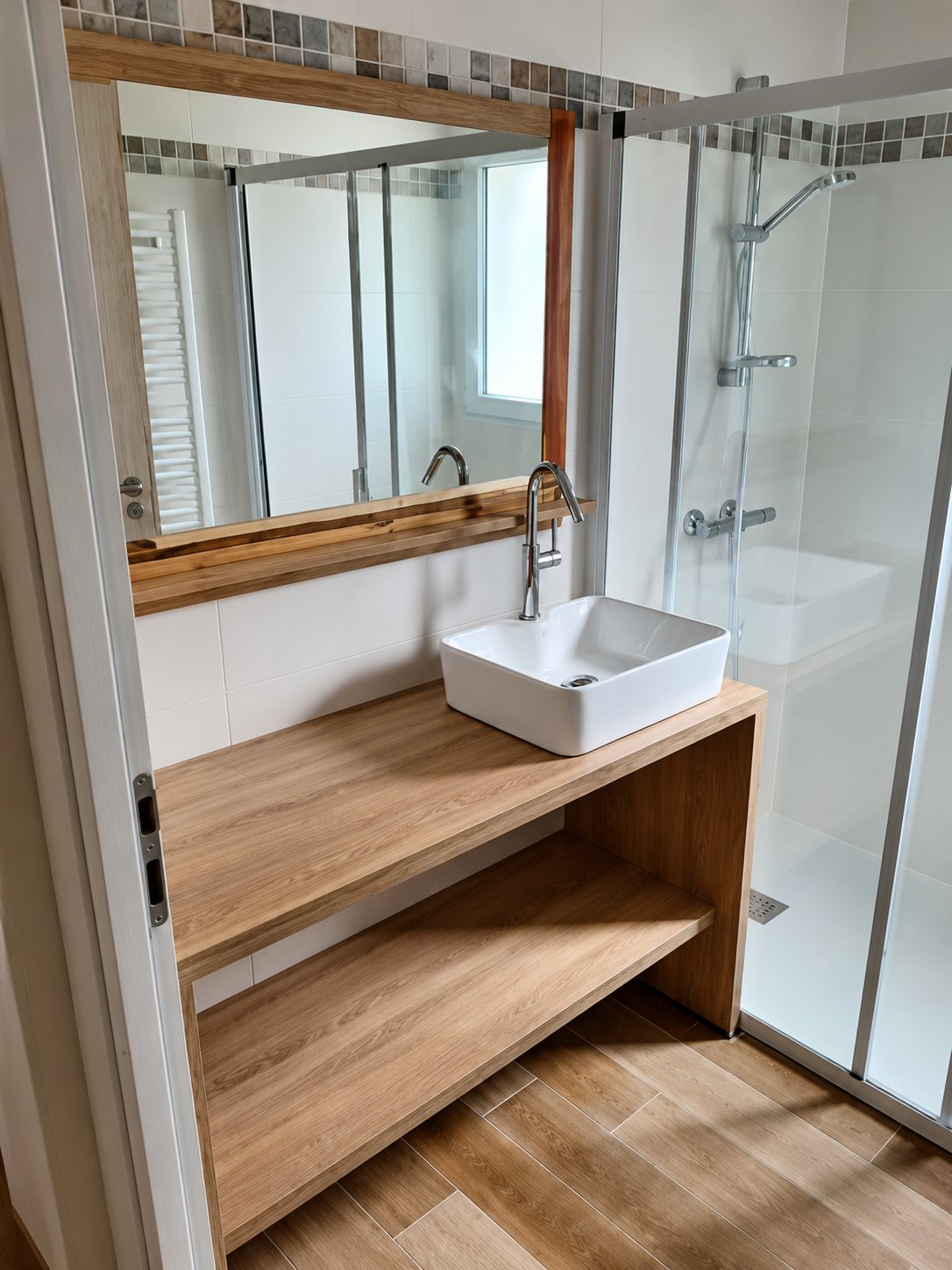 Meuble vasque en bois clair et miroir dans une salle de bain avec douche