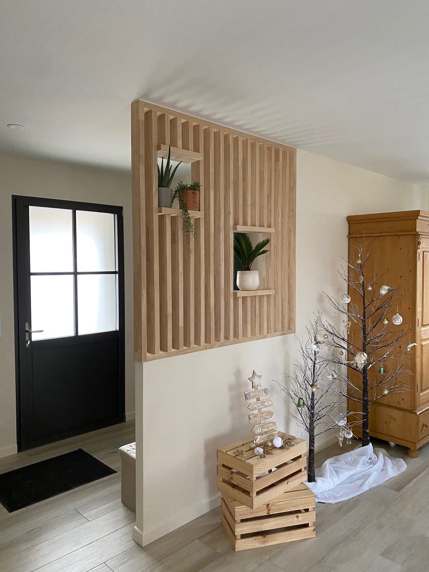 Claustra en bois dans une entrée, avec une porte noire