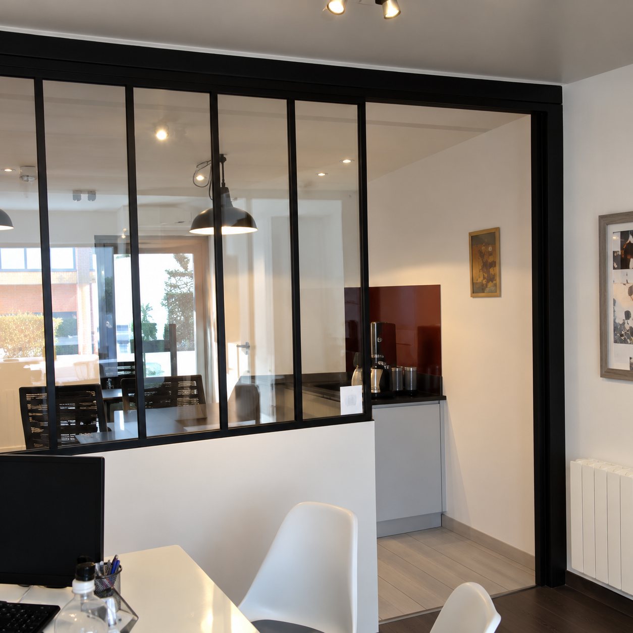 Verrière noire entre une salle à manger et une cuisine